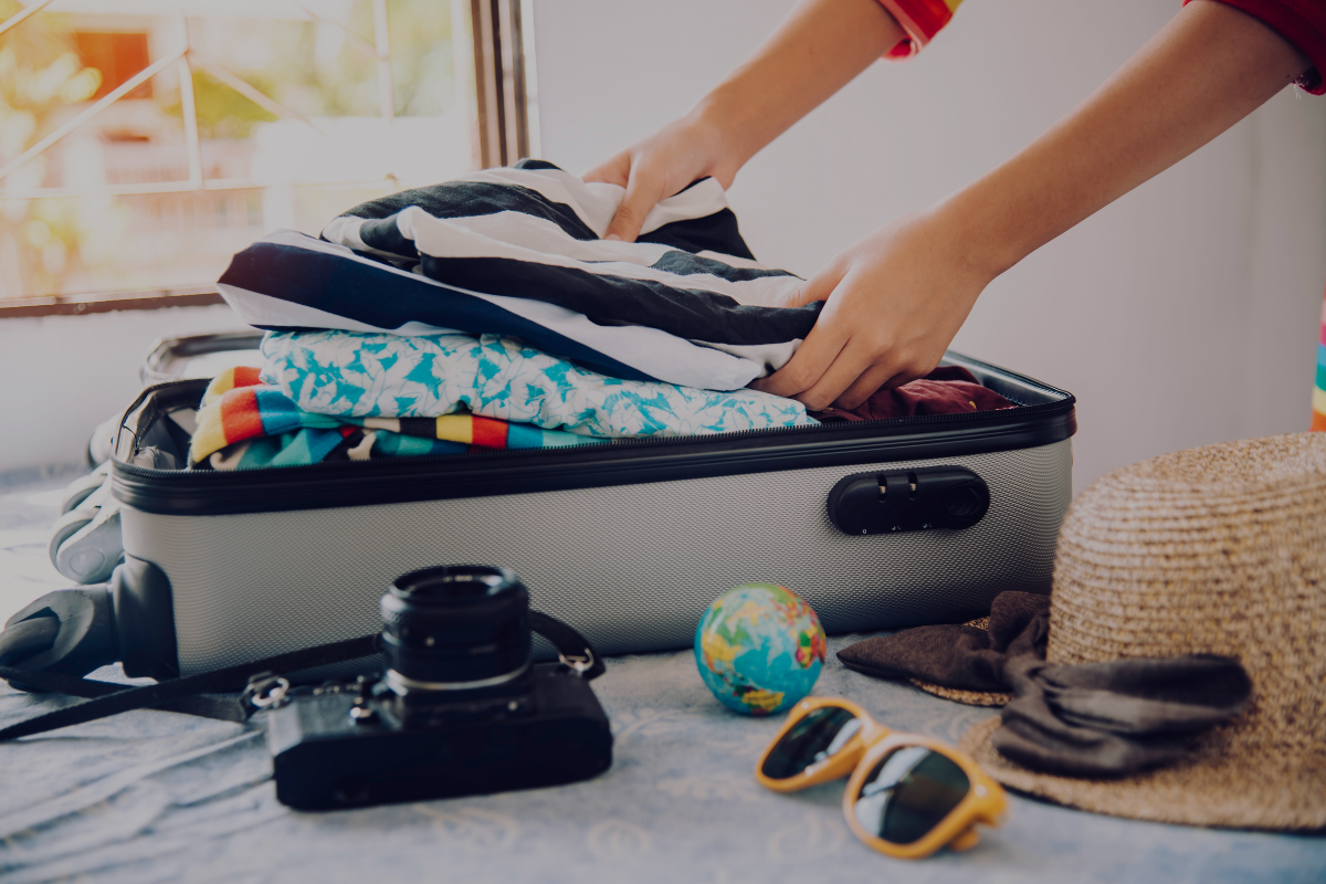 Valise en cours de préparation avec appareil photo, lunettes et chapeau